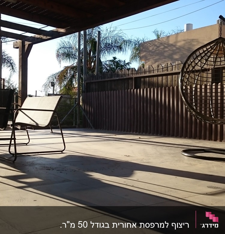 מרפסת עם רצפת בטון, גדר עץ וכיסאות מתכת